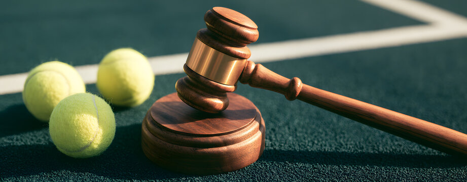 Wooden gavel rests on the tennis court next to two balls, symbolizing sports law and justice in athletic competitions, fair play decisions, and dispute resolution.