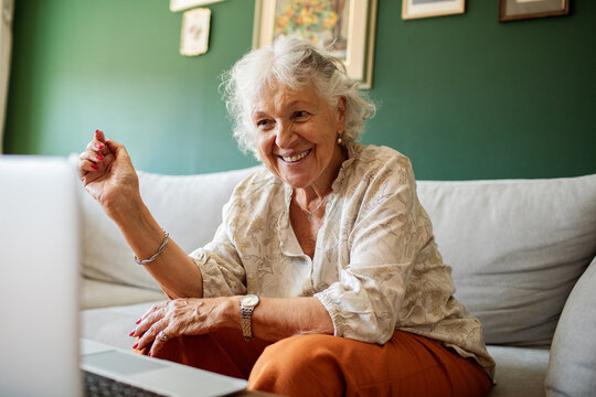 Smiling senior woman video calling on laptop at home