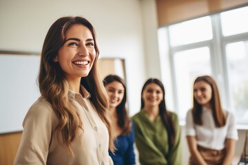 Obraz premium Happy teacher standing in a classroom with smiling female students in the background