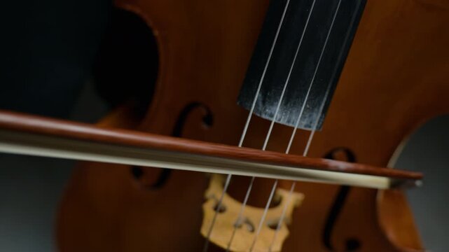 Caucasian male musician playing cello, drawing bow across strings in close-up shot. Clip is perfect for classical music education promos, orchestra concert advertisements or artistic documentaries