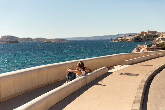 Deux jeunes amies assises au soleil sur le banc de la Corniche Kennedy &agrave; Marseille et discutant face &agrave; la mer bleue