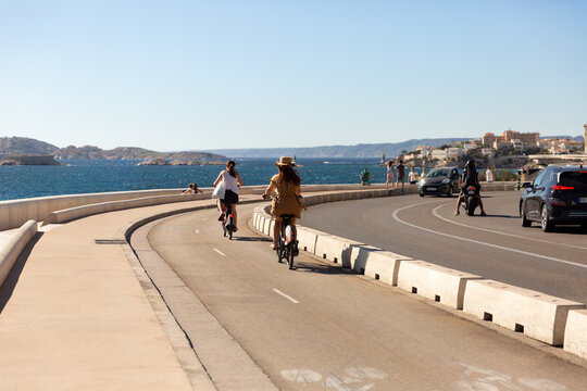 Deux femmes &agrave; v&eacute;lo vues de dos sur la piste cyclable de la Corniche Kennedy &agrave; Marseille face &agrave; la mer