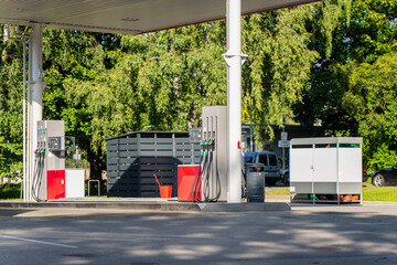 Fuel dispensers stand in the shade of a filling station canopy featuring fuel prices economy supply chain gasoline, showing fuel retail infrastructure and forecourt equipment © K