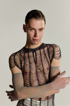 A young, handsome, non binary individual poses elegantly, radiating style and self expression.