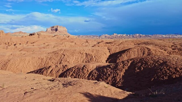 Golden morning sunlight highlights mushroom-shaped sandstone hoodoos along the scenic road winding through Goblin Valley State Park in Utah