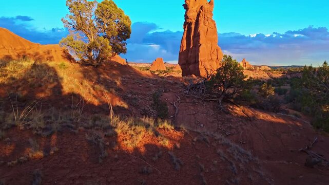 Warm golden sunset light illuminates towering sandstone chimneys and rugged eroded badlands across Kodachrome Basin State Park in Utah