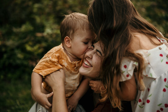Mother smiling while son and daughter kissing cheek