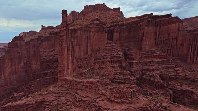 Panoramic aerial flight beside dramatic sandstone Fisher Towers overcast evening skies near Moab Utah