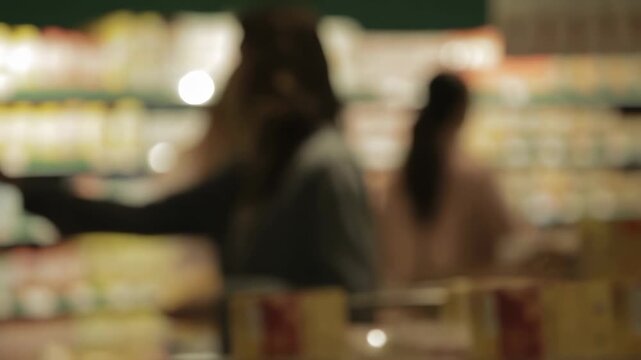 Blurred shoppers browse a brightly lit grocery store aisle. Retail advertising, grocery store promotion, and consumer behavior education.