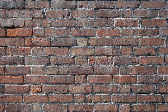 Old brick wall texture background with mixed brown and orange bricks, rough mortar and natural color variation