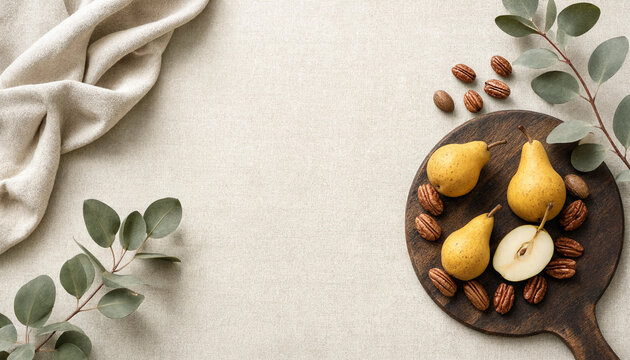 Top view of pears and pecans on a wooden board with eucalyptus leaves and fabric