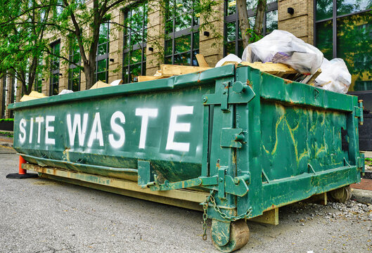 Commercial dumpster with site waste outside a construction site. USA 2026