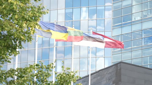 Three national flags mark the entrance of a mirrored headquarters, part of the quiet visual language every multinational uses to present itself to visitors.