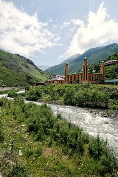 General view of modern Olgeti village mosque with minarets and green domes standing near Armkhi river in Dzheyrakh region of Ingushetia Russia presenting caucasian mountain travel landscape concept
