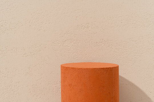 Product Presentation Scene made with Single Terracotta Cylinder Podium on Warm Beige Textured Wall Background with Copy Space