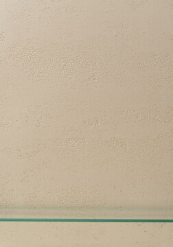 Empty Glass Shelf on Travertine Textured Beige Wall &mdash; Cosmetic Display Template with Copy Space. Vertical Photography.