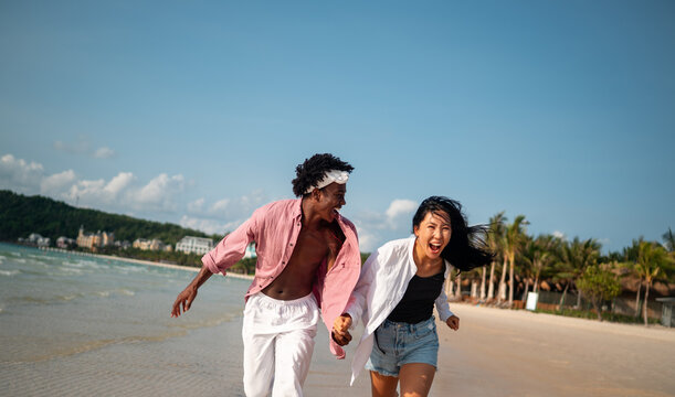 Happy young couple embracing and laughing on a tropical beach during summer vacation