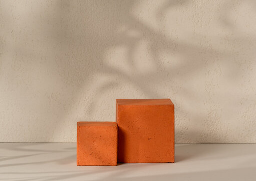 Terracotta textured cube podium placed side by side on a white surface against a beige textured wall with a leaf shadow overlay, ideal for geometric cosmetic product display and beauty advertising.
