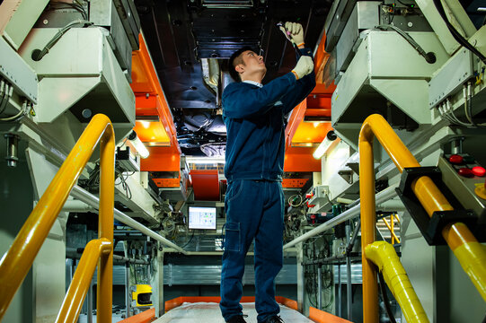 Auto Worker Inspecting Car Chassis
