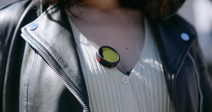 Close up of a female journalist or vlogger clipping a small wireless microphone to her sweater before an interview or a recording