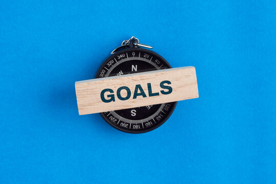A piece of paper displaying the word GOAL alongside a compass, representing business strategy, teamwork, and achieving shared objectives.