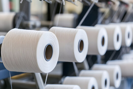 White yarn spools are moving on the textile manufacturing machine