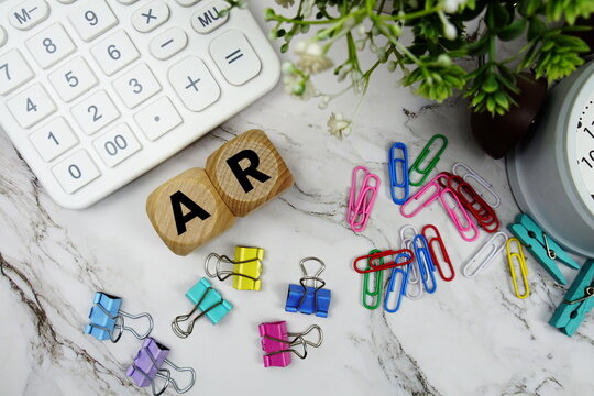 AR Accounts Receivable alphabet letters with calculator and alarm clock on marble background