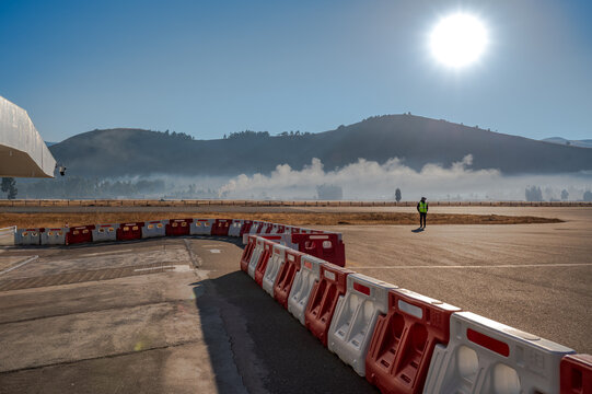 Morning mist drifts across Francisco Carl&eacute; Airport in Jauja, Peru. A ground worker stands beside safety barriers under bright Andean sun.