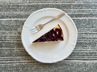 Directly above view of berry cheesecake slice on white porcelain plate with dessert fork © Marta