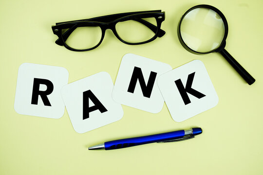 RANK alphabet letters with magnifying glass, eye glasses and pen on yellow background