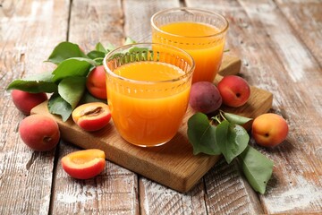 Glasses of tasty apricot juice, fresh fruits and leaves on wooden table, closeup © New Africa
