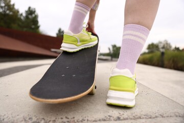 Woman riding skateboard on city street, closeup © New Africa