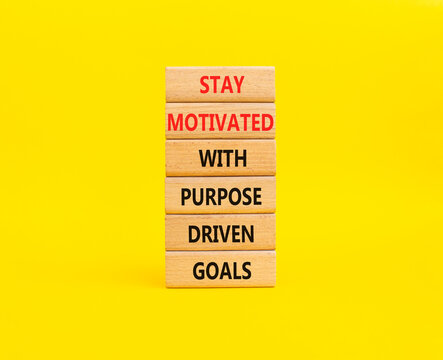 Stay motivated with purpose driven goals symbol. Concept words stay motivated with purpose driven goals on wooden blocks. Beautiful yellow background. Business concept. Copy space.