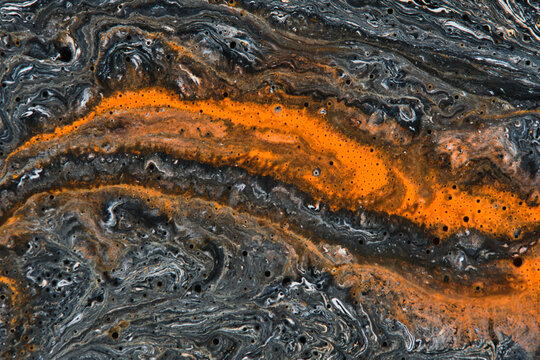 Bright orange fluid vein flowing through dark textured marble background with tiny bubble details.
