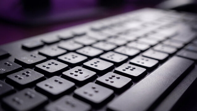 Close up of a computer keyboard with Braille dots for blind and visually impaired people. Assistive technology for accessibility, inclusive digital workspace, modern disability equipment