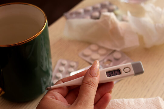 Woman holding digital thermometer showing high fever cold and flu treatment background