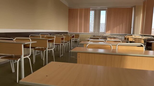 Empty school classroom with wooden desks and chairs, quiet study space before lesson.