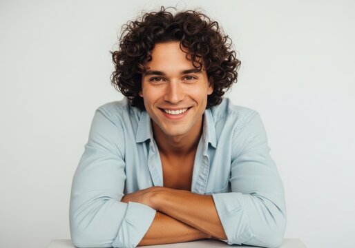 Smiling man with curly hair wearing light gray shirt