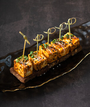Sandwiches with pickled soft cheese on dark background