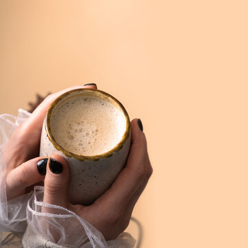Pumpkin latte in female hand. Hands holding mug with warm drink
