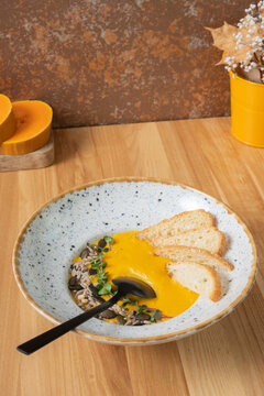 A plate of mashed pumpkin soup on wooden table. Autumn menu concept