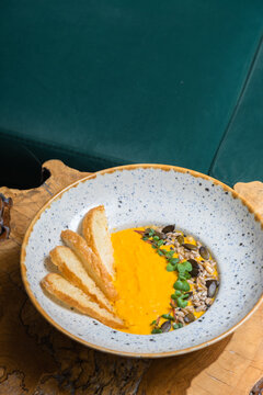 A plate of mashed pumpkin soup on wooden table. Autumn menu concept