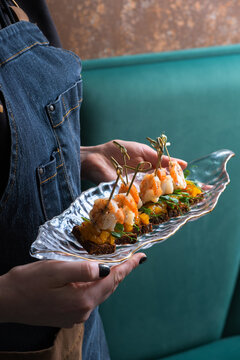 Canapes with shrimp chutney and mango on a plate in the hands of a waitress. Service area concept