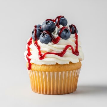 Freshly baked vanilla cupcake topped with light whipped cream, juicy blueberries, and a sweet berry compote drizzle on a neutral background, treat, confection, icing