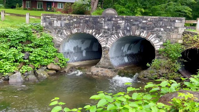 Stream flowing through culverts under stone bridge
