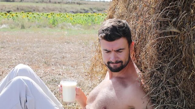 Attractive Shirtless Farmer Drinking Fresh Milk in Sunflower Field