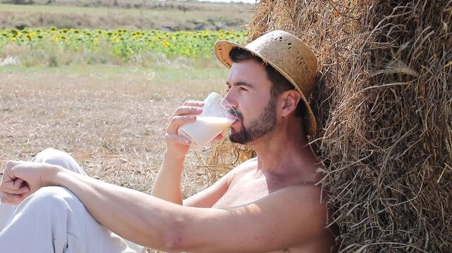 Attractive Shirtless Farmer Drinking Fresh Milk in Sunflower Field