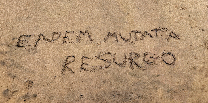 Hand written beach sand. Eadem mutata resurgo  is a Latin phrase that translates to Although changed, I arise the same.