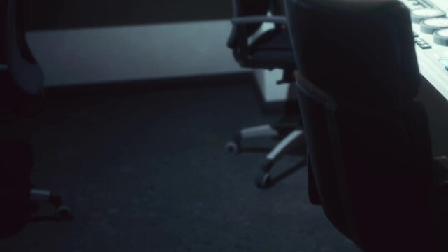 A quiet office setting shows empty chairs and a desk during the late hours of the day. The scene suggests a time when work has paused and the space is unoccupied.