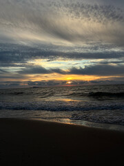 Obraz premium Dramatic golden sunset over stormy sea waves with flying seagull and expressive clouds